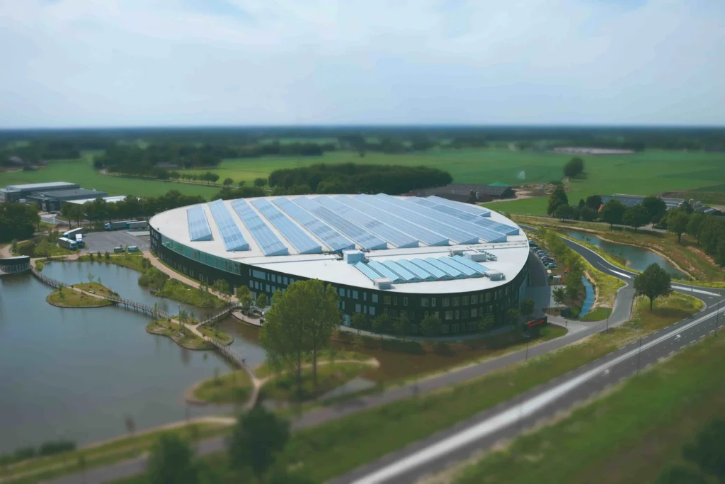 Gebouw met zonnepanelen in groen landschap.