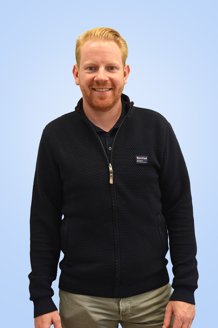 Lachende man in zwarte trui met blauwe achtergrond.