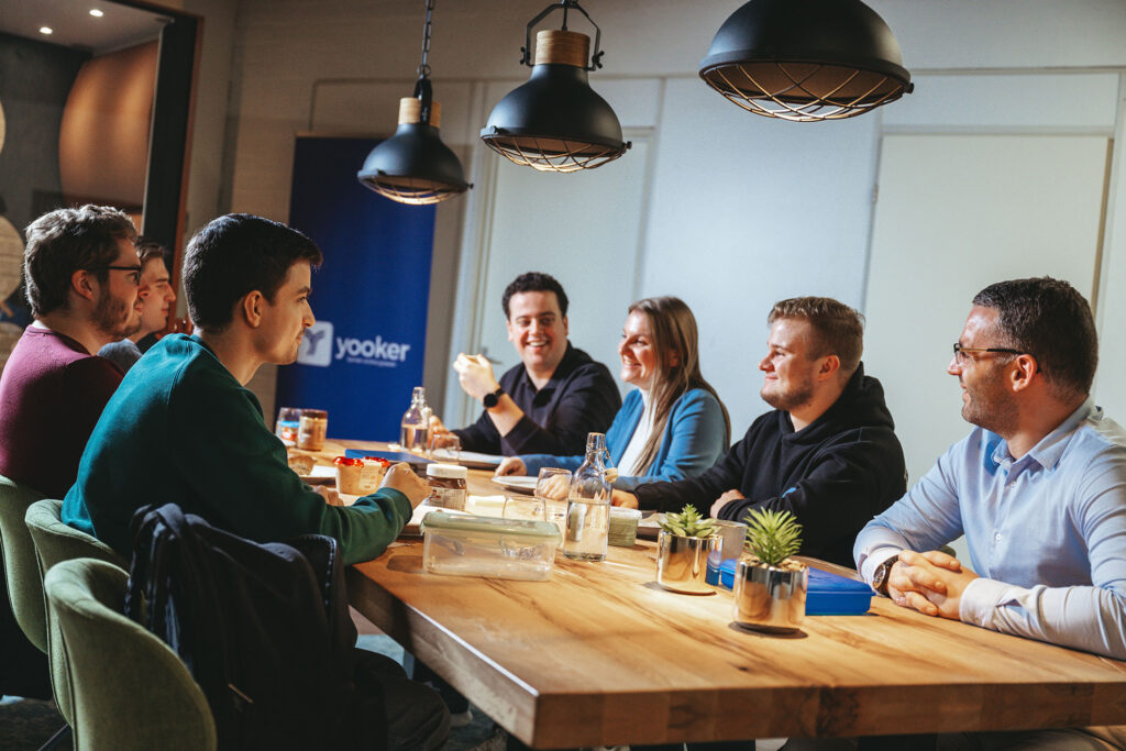 Mensen vergaderen rond een houten tafel in kantoor.